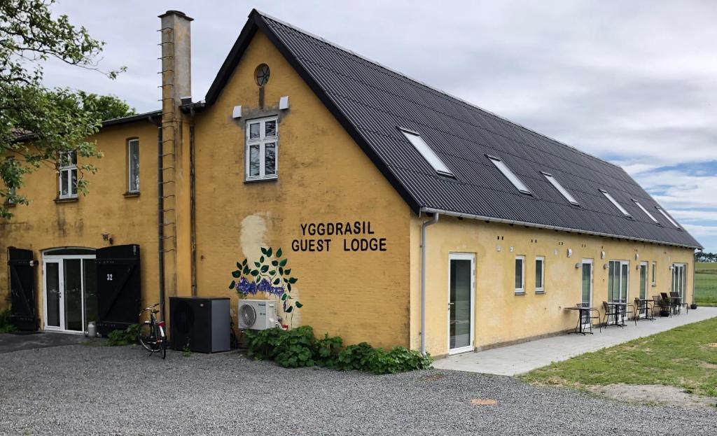 ein großes gelbes Gebäude mit schwarzem Dach in der Unterkunft Yggdrasil Guest Lodge in Gudhjem