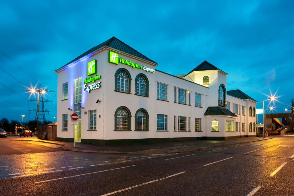 a white building with neon signs on a street at Holiday Inn Express London Chingford, an IHG Hotel in London