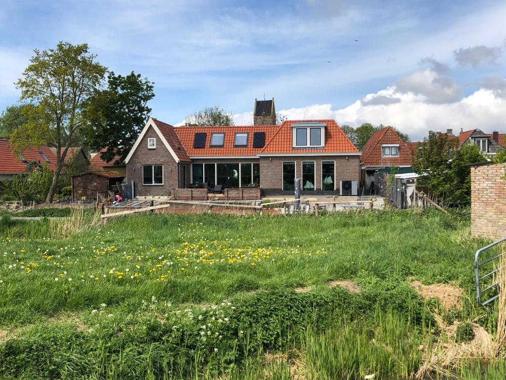 una casa con un campo abierto delante de ella en B&B De Gulden Halsband Pingjum, en Pingjum