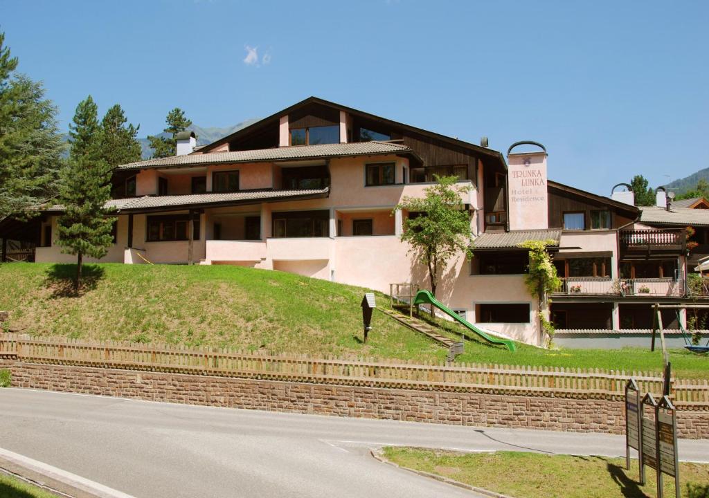 a house on a hill with a road in front of it at Residence Trunka Lunka in Cavalese