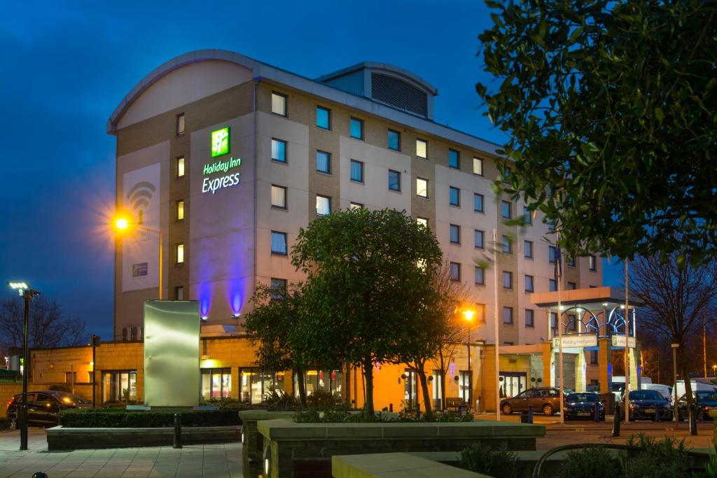 un grand bâtiment avec un panneau la nuit dans l'établissement Holiday Inn Express London - Wandsworth, an IHG Hotel, à Londres