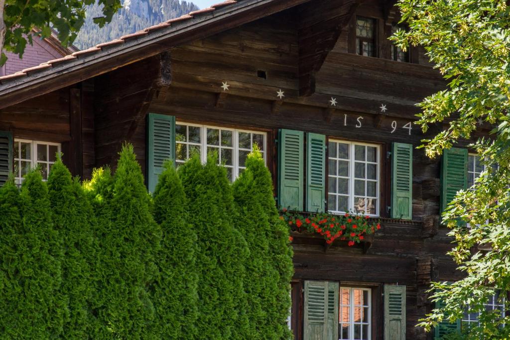 drewniany dom z zielonymi okiennicami i drzewami w obiekcie OldSwissHome w mieście Matten
