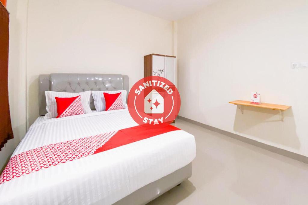 a bedroom with a bed with a red sign on it at Super OYO Capital O 3092 Falah Residence Syariah in Padang