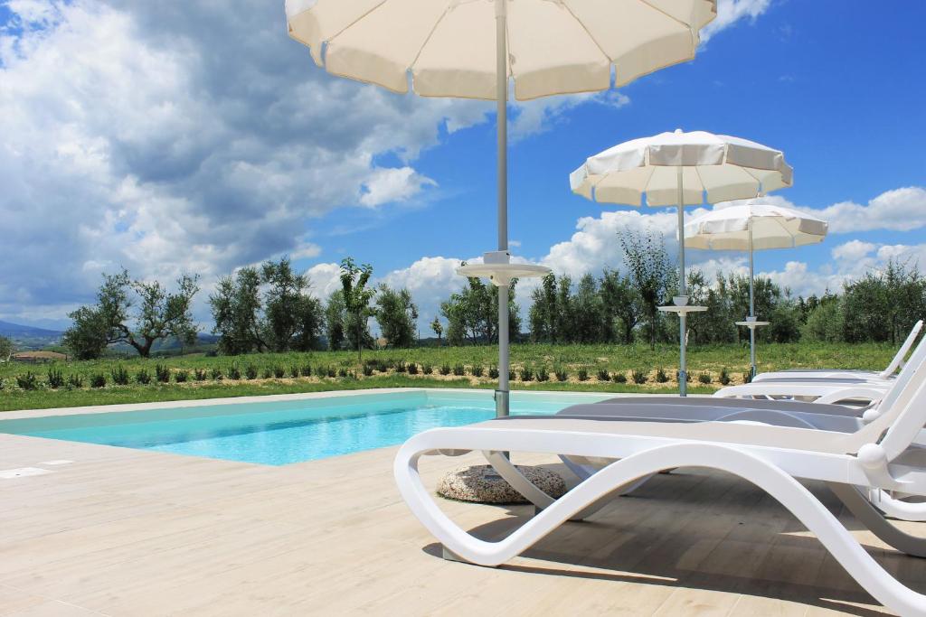 un par de sillas y una sombrilla junto a la piscina en Verdemare, en Acquaviva Picena