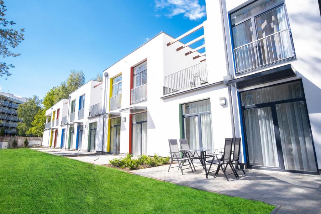 a white building with chairs and tables in a yard at Szent Bernadett Családi Apartmanház in Siófok