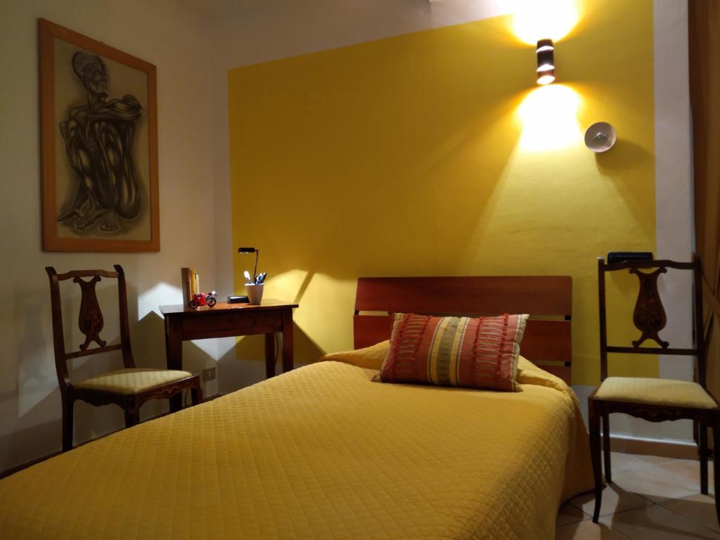 ein Schlafzimmer mit einem Bett mit zwei Stühlen und einer Lampe in der Unterkunft I giochi di Lupo in Pianoro