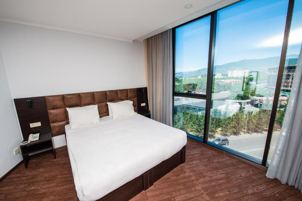 a bedroom with a bed and a large window at Hotel Shine Palace in Tbilisi City
