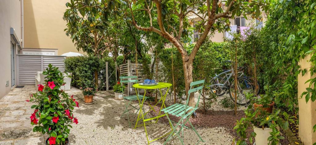 einen Garten mit einem Tisch, Stühlen und einem Baum in der Unterkunft Al Giardino Del Nespolo in Polignano a Mare
