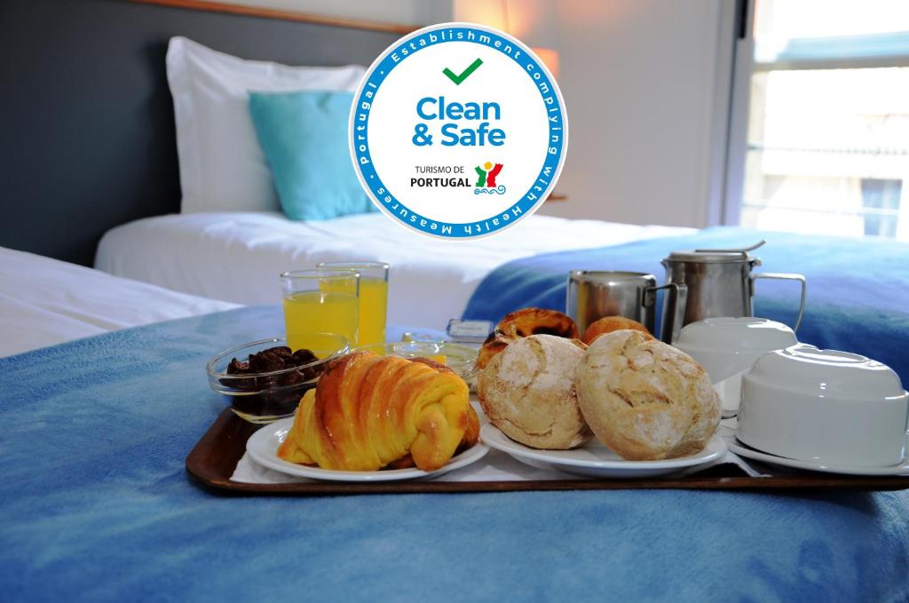 ein Tablett mit Frühstückslebensmitteln auf einem Bett in der Unterkunft Hotel Girassol in Porto