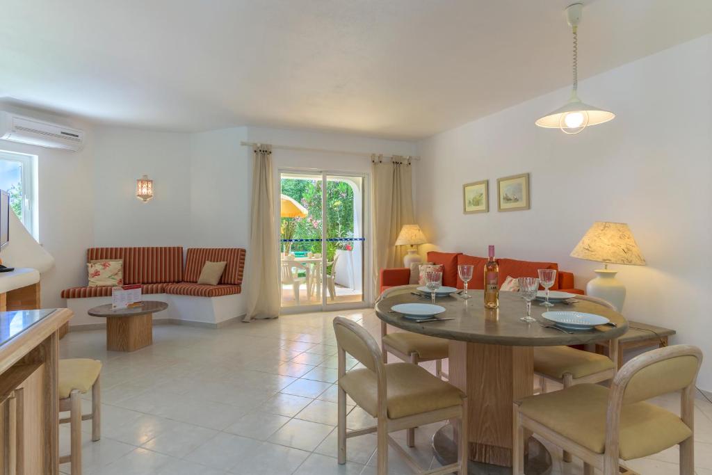 uma sala de estar com mesa e cadeiras em FLH Balaia Village Apartment with Pool I nos Olhos de Água