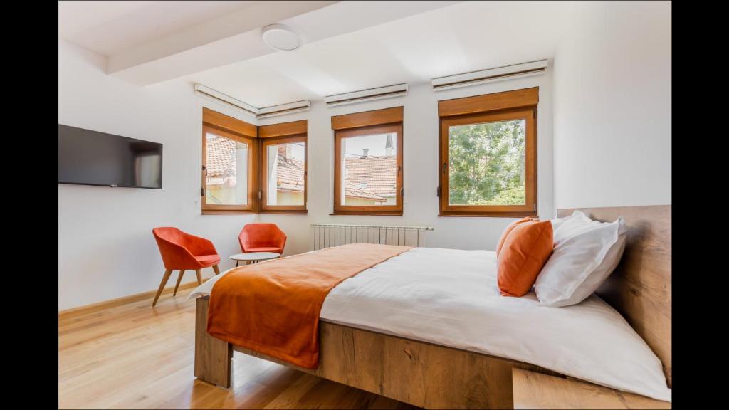 a bedroom with a bed and a chair and windows at Apartments RUBIK in Sarajevo