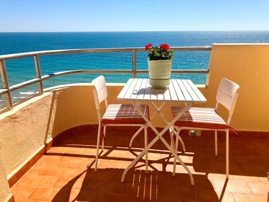 einen Tisch und Stühle auf einem Balkon mit Meerblick in der Unterkunft GATU Villa Bani con terraza y vista frontal al mar in Cádiz