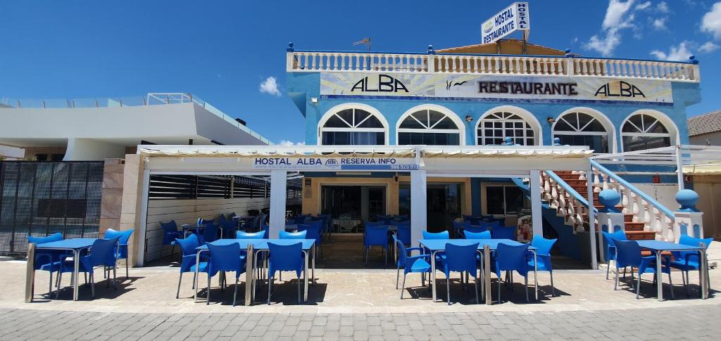 a group of blue tables and chairs in front of a building at Hostal Alba in La Mata