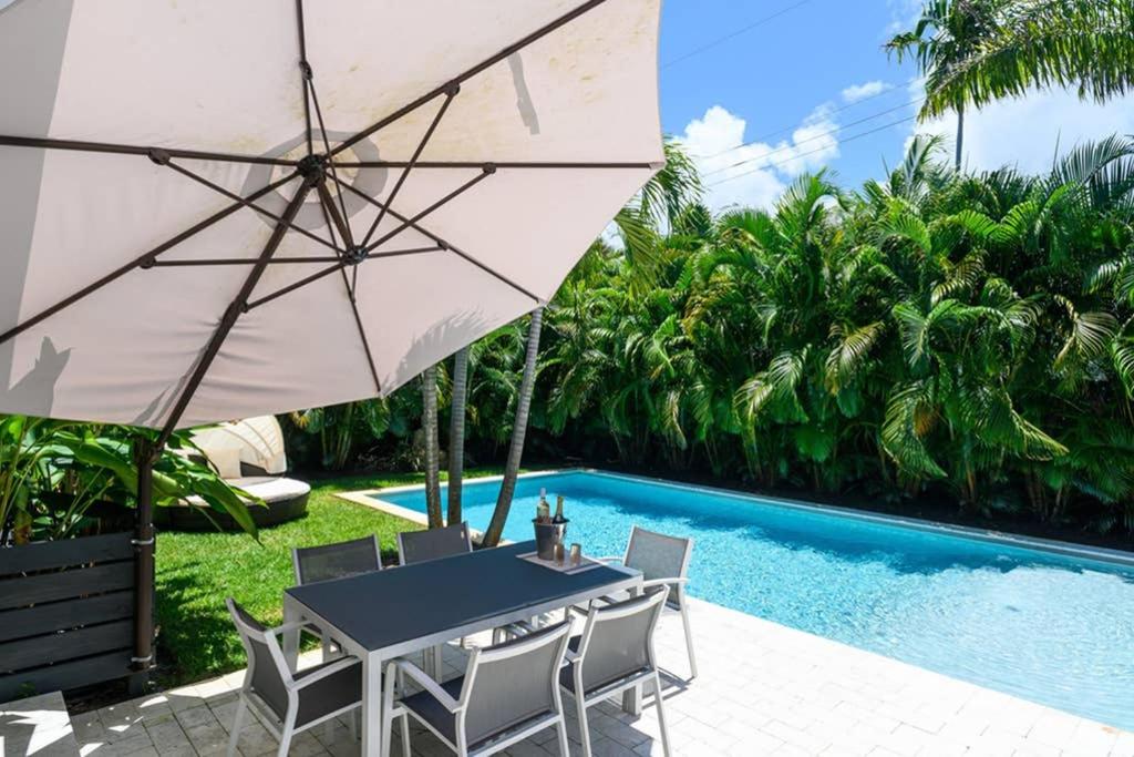 a table with an umbrella next to a swimming pool at Paradise Home 3 BR with Heated Pool close to Beach in Fort Lauderdale