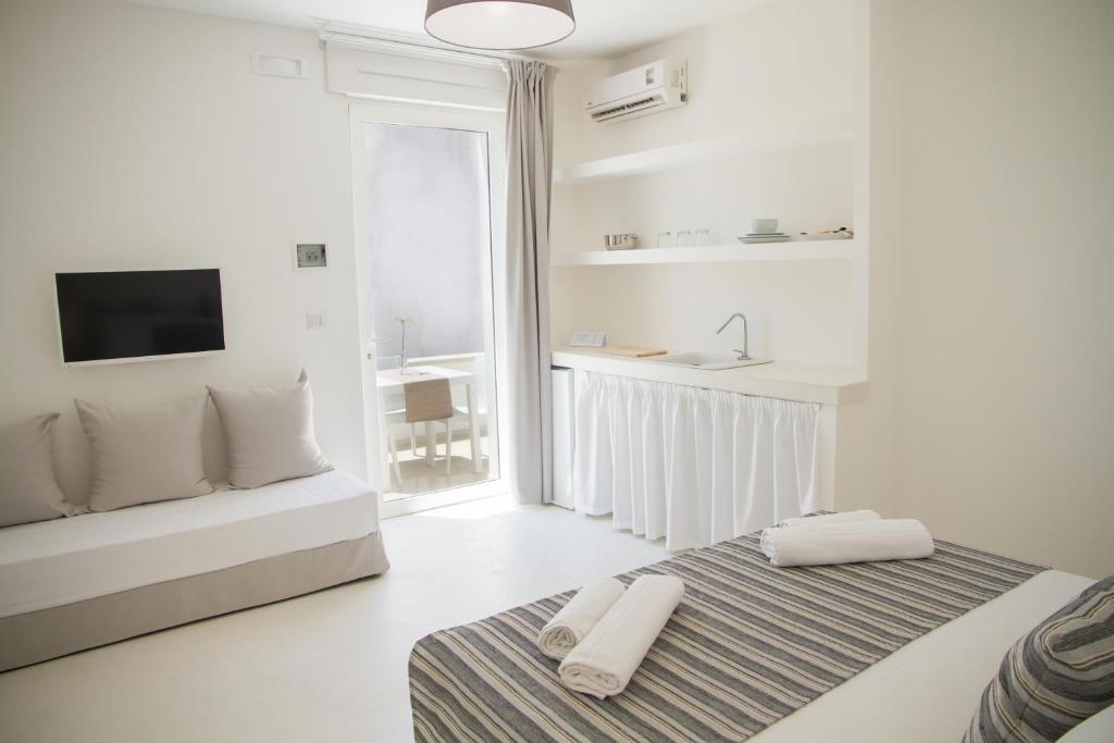 a white room with a bed and a couch and a sink at Dimora Ausentum in Torre San Giovanni Ugento