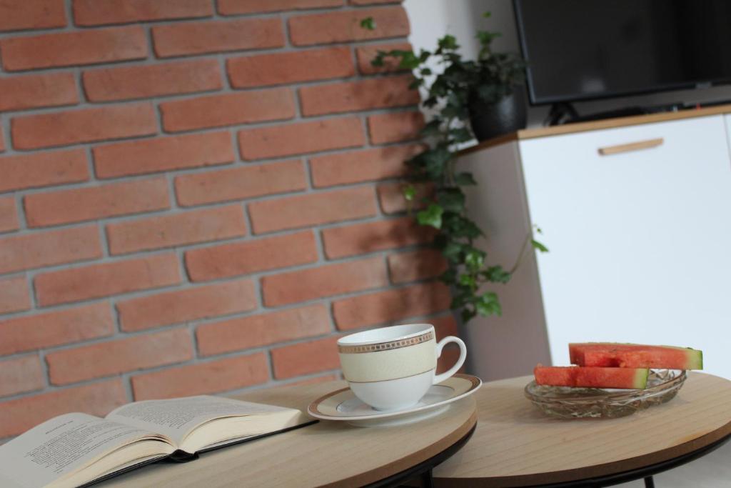 uma chávena de café numa mesa com um livro em Apartament Kliwia em Tolkmicko