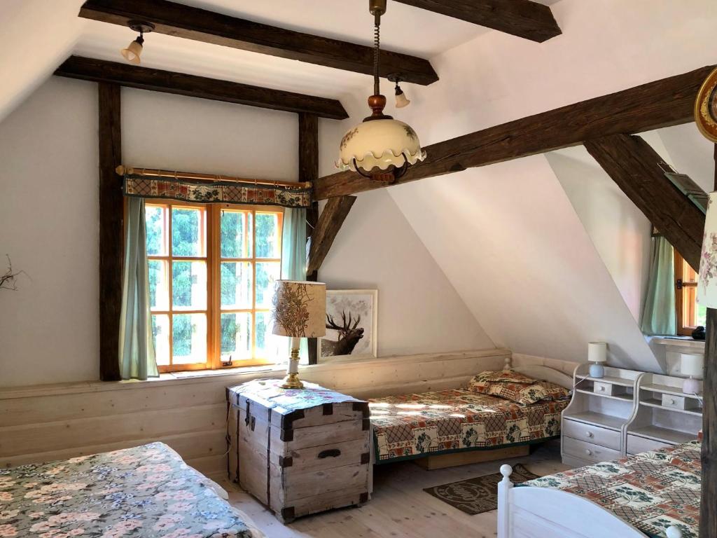 a attic bedroom with two beds and a window at Sielski Zakątek Tokary in Tokary