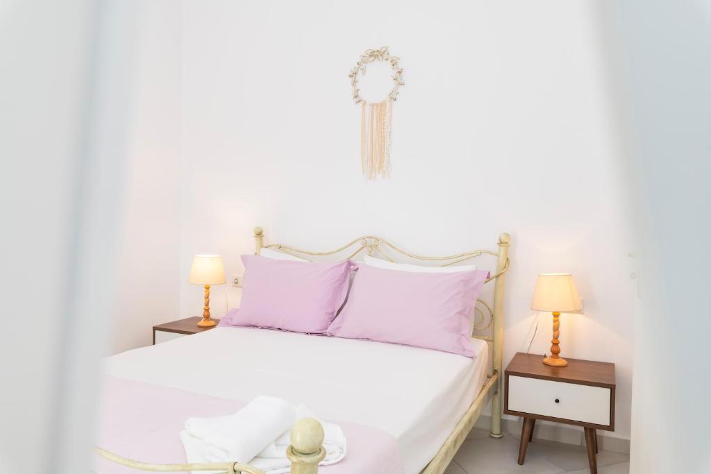 ein Schlafzimmer mit einem weißen Bett und zwei Nachttischen in der Unterkunft Arsis Houses, Big House in Antiparos