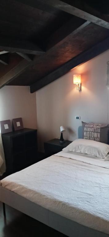 Un dormitorio con una cama blanca con una luz en la pared en La scalinata del Borgo en Montecorvino Rovella