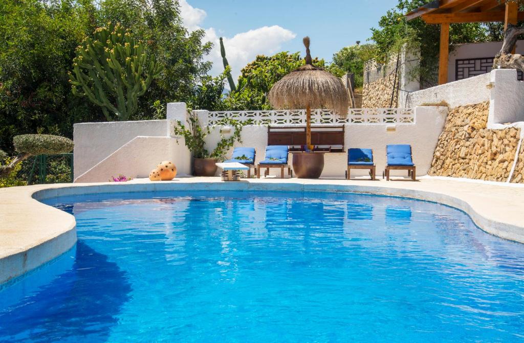 een zwembad met blauwe stoelen in een tuin bij Villa Samar Altea Grupo Terra de Mar, alojamientos con encanto in Altea