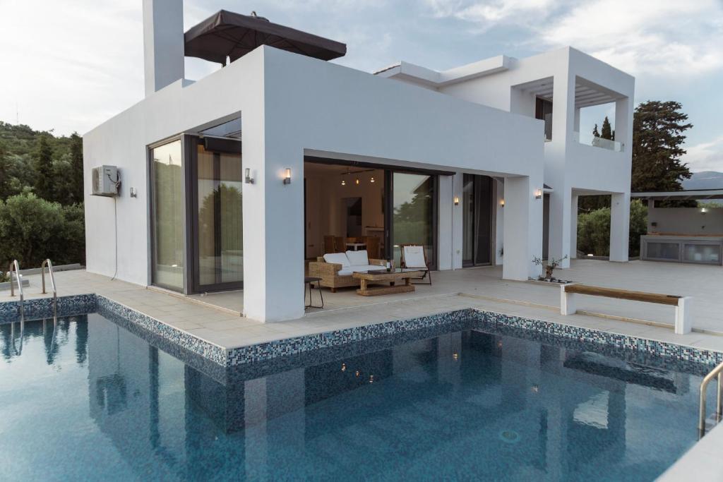 una casa blanca con piscina frente a ella en Olive View Villa, en Dhíkella