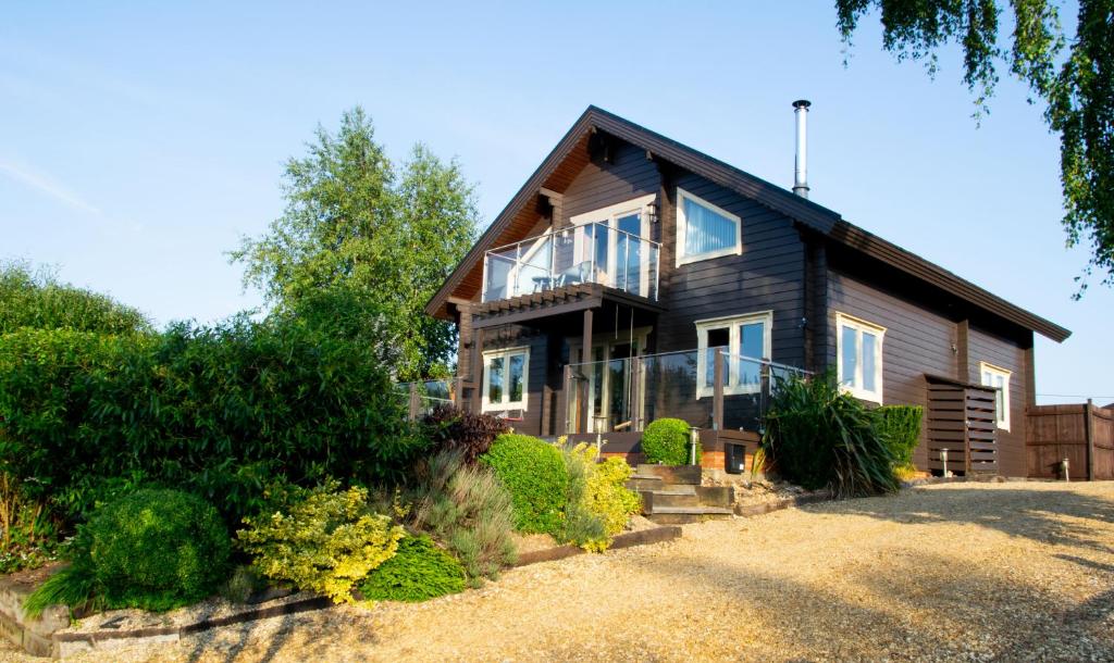 Pine Tree Lodge - Pentney Lakes في Pentney: منزل خشبي بأبواب زجاجية ونوافذ