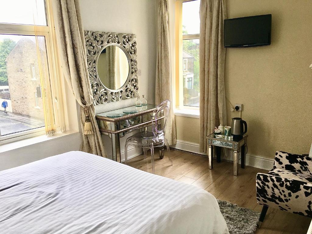 a bedroom with a bed and a vanity and a mirror at Highfield Guesthouse in Skipton