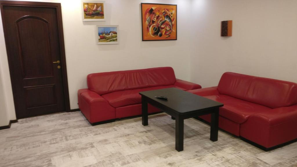 una sala de estar con 2 sofás rojos y una mesa. en Studio Mary en Constanza