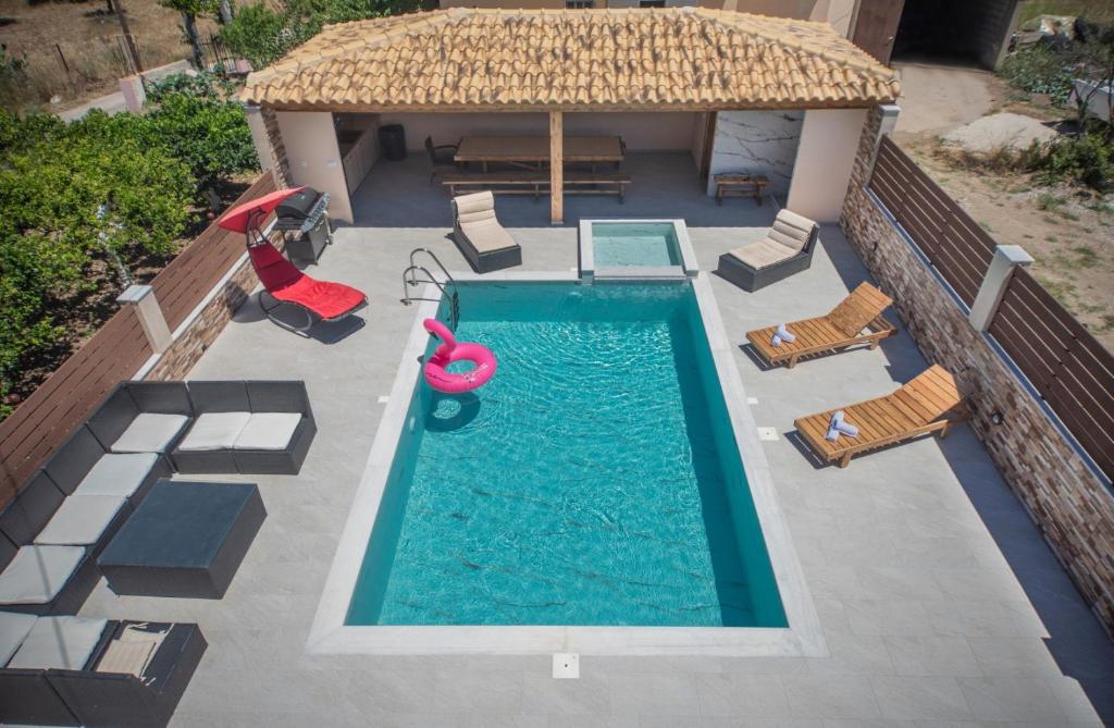 einen Blick über einen Pool mit Stühlen und einem Sonnenschirm in der Unterkunft M & S Villa - 3 bedroom villa with heated pool in Pastida