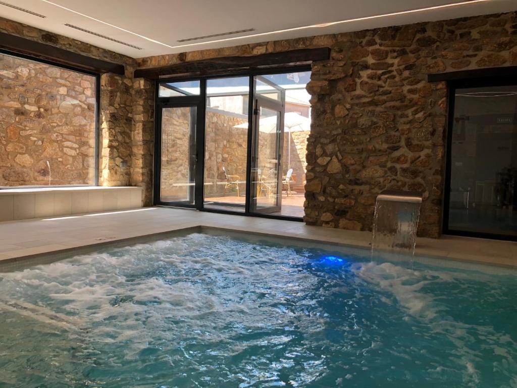 a swimming pool in a house with a stone wall at Casa Rural La Calzada in El Payo