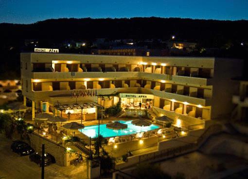 een groot gebouw met een zwembad in de nacht bij Hotel Afea in Agia Marina Aegina