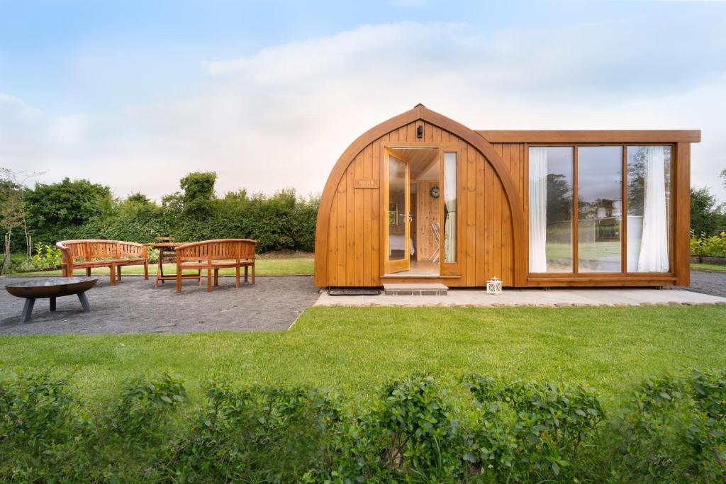 a small wooden house in a garden with grass at Orchard Glamping in Catterall