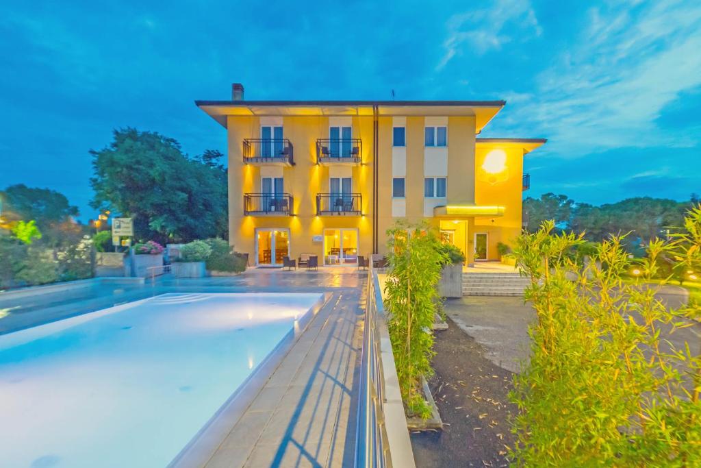 a yellow building with a swimming pool in front of it at Hotel Nuova Barcaccia in Peschiera del Garda
