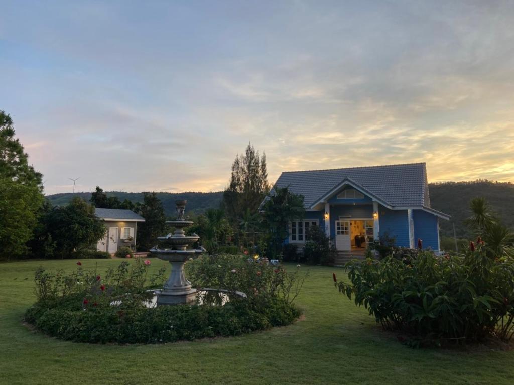 a house with a fountain in front of a yard at Misty English Cottage in Ban Non Na Yao