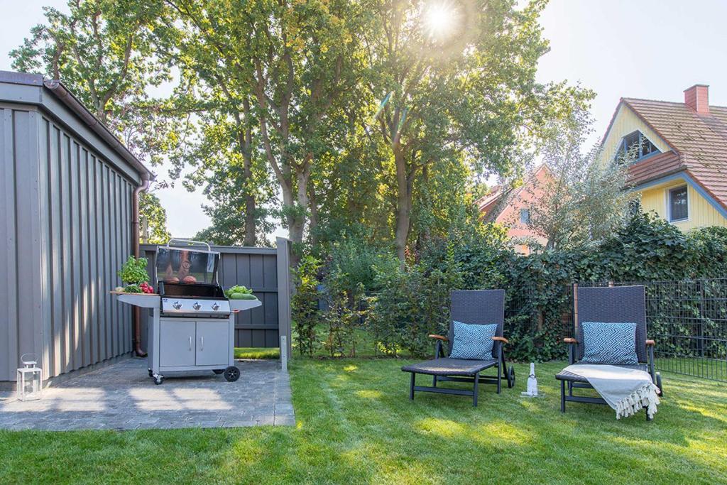 Un patio trasero con parrilla y dos sillas en el césped. en Wildrose, en Zingst