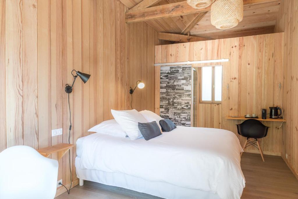 um quarto com uma cama branca e paredes de madeira em Centre Cap-ferret, les chambres du phare, bassin em Cap Ferret