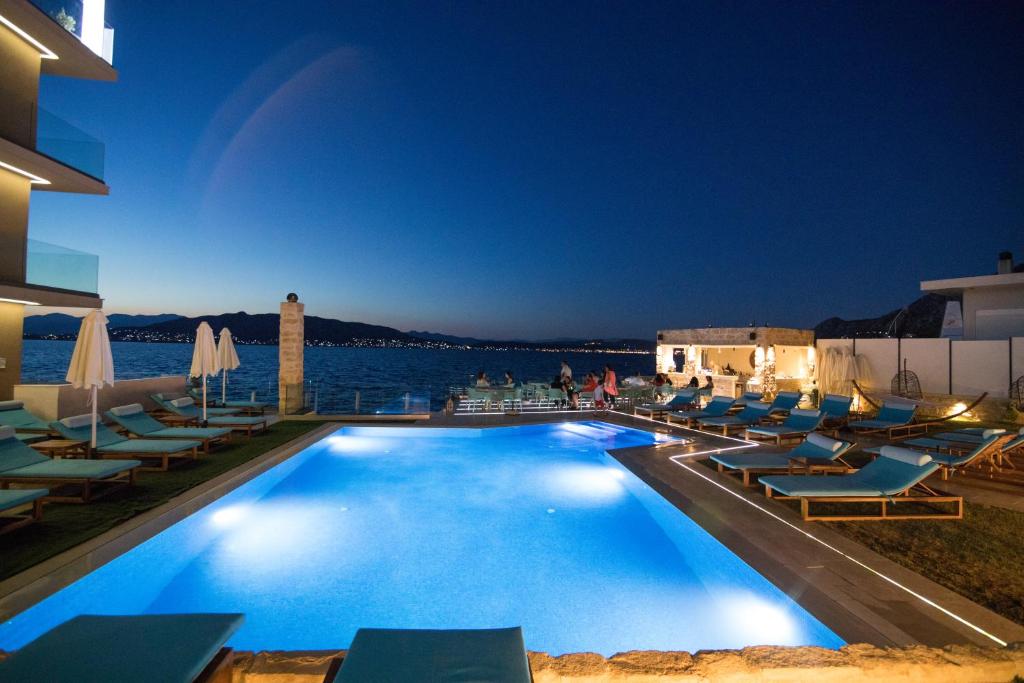 a swimming pool with lounge chairs and the water at night at Aianteion Bay Luxury Hotel & Suites in Aiándion