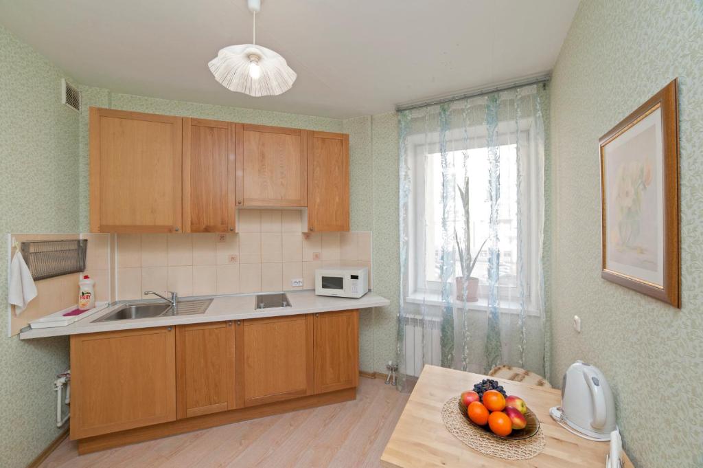 a kitchen with wooden cabinets and a bowl of fruit on a table at Apartments on Kuznechnaya 79 in Yekaterinburg