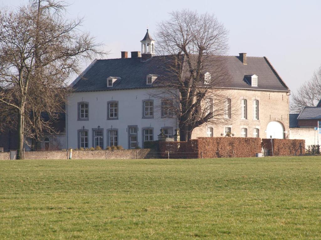 a large white house with a field in front of it at Buitenplaats Bemelen in Bemelen