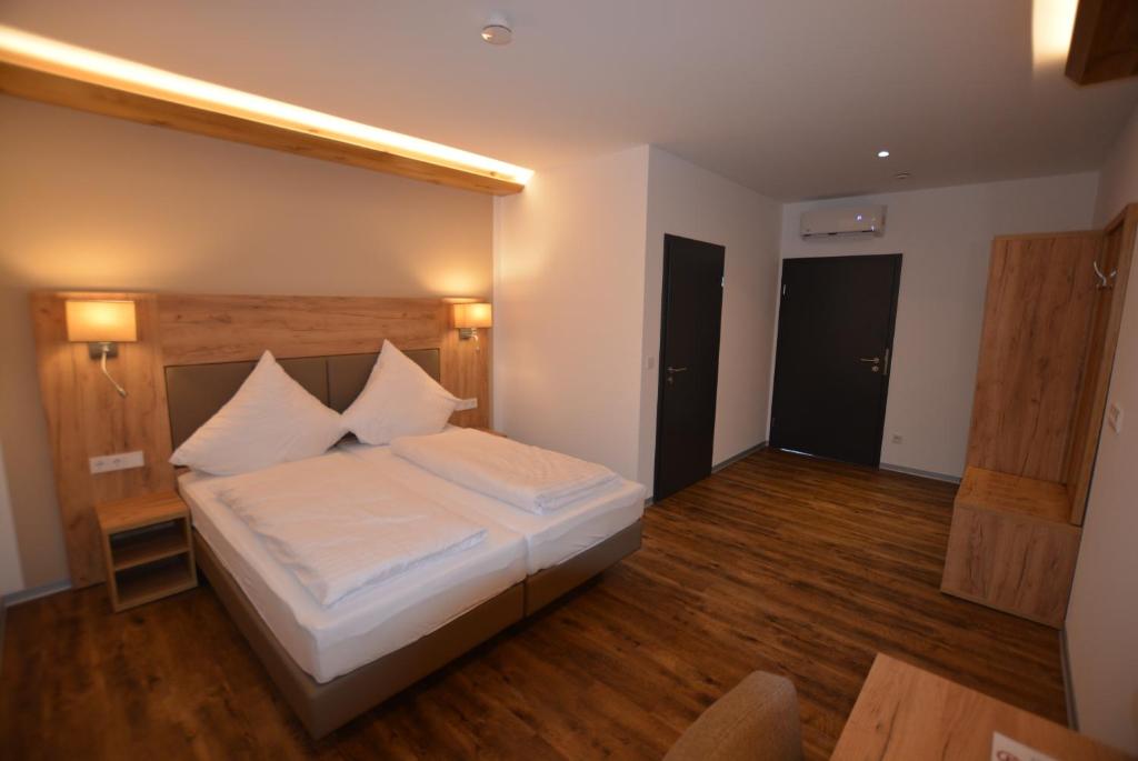 a bedroom with a bed with white sheets and wooden floors at GS DiePension in Griesheim