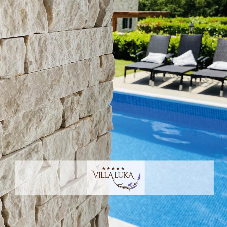 a stone wall next to a swimming pool at Villa Luka in Višnjan