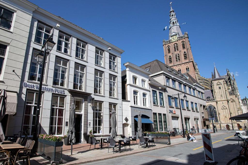 een stadsstraat met witte gebouwen en een klokkentoren bij Good Seasons City Centre Hotel Den Bosch in Den Bosch