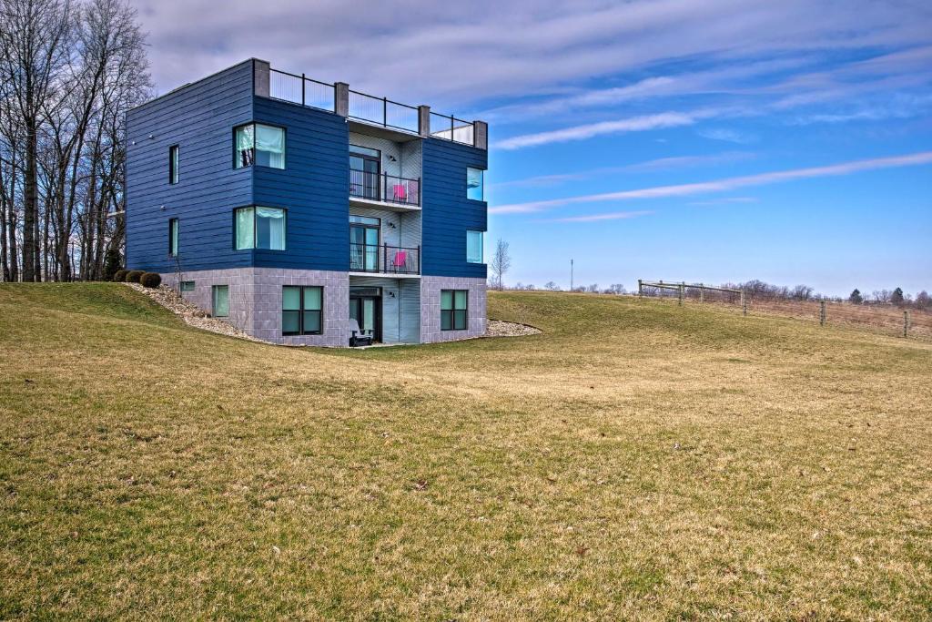 a blue building on top of a grassy hill at Luxe Amish Country Apartment with Rooftop Terrace! in Millersburg