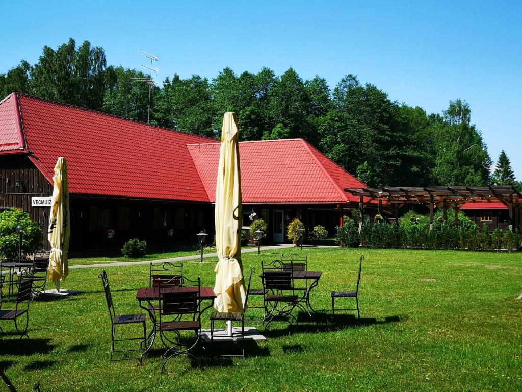 a group of tables and chairs with umbrellas in front of a building at Viesu nams Vecmuiža in Tūja