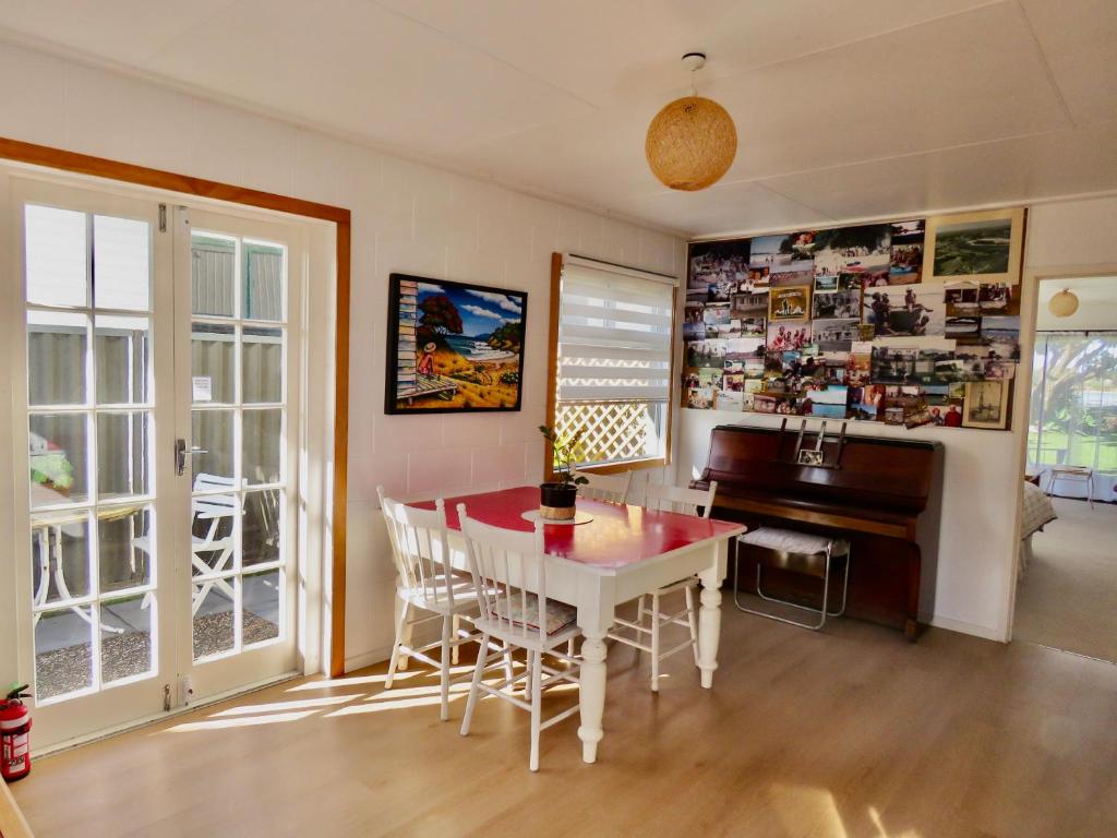 旺阿雷的住宿－Pohutukawa Bach，一间带桌子和钢琴的用餐室