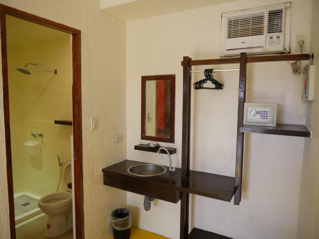 a bathroom with a sink and a mirror and a toilet at Lazy Dog Bed & Breakfast in Boracay