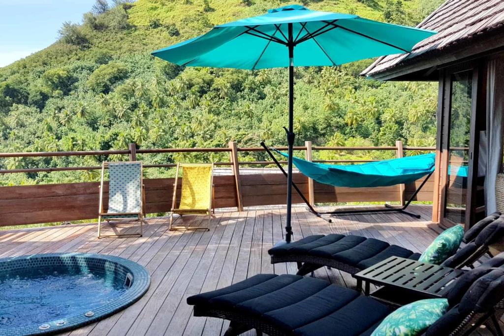 a patio with a hammock and an umbrella at Villa Anuanua by Tahiti Homes in Papetoai