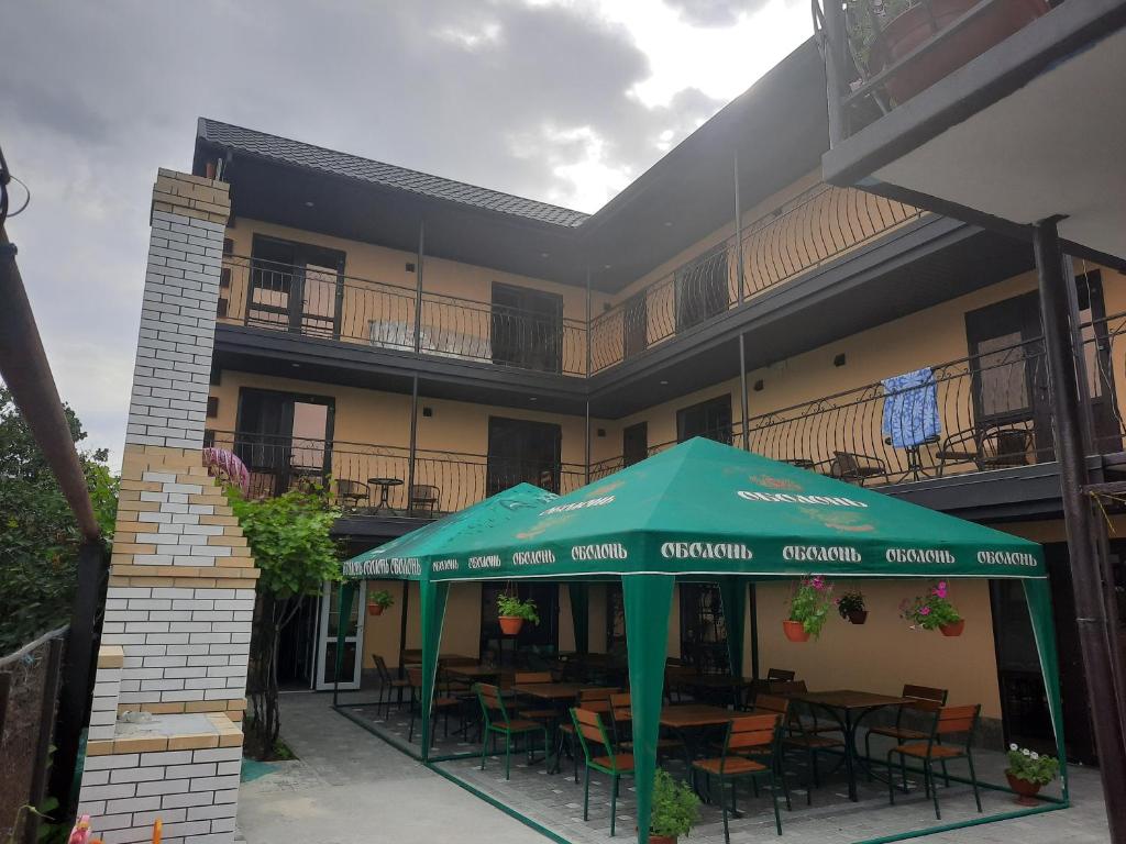 a restaurant with tables and chairs under a green umbrella at Guest house Viola in Berdiansk