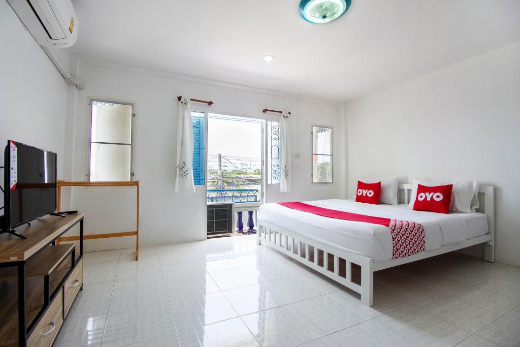 a white bedroom with a large bed and a television at OYO 908 Sabai Place in Hua Hin
