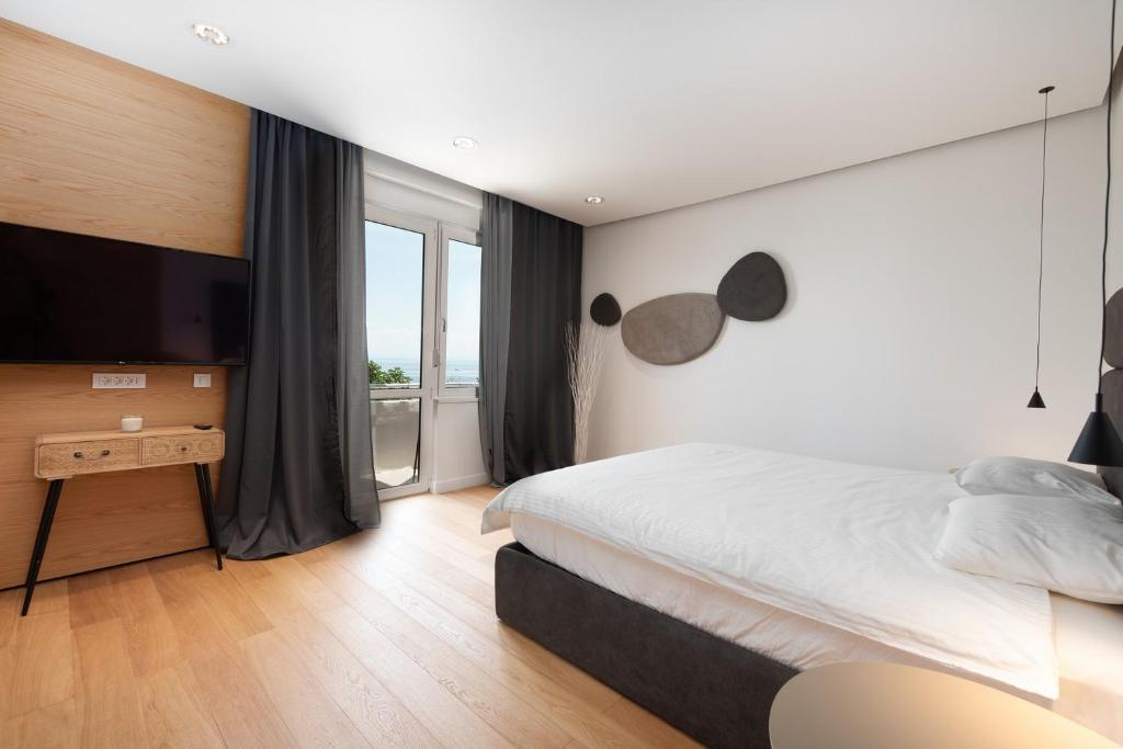 a bedroom with a large bed and a television at Beachfront Apartment Rosa del Mar Jardin in Mošćenička Draga